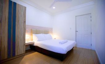 a clean and well - organized bedroom with a white bed , hardwood floors , and a wooden dresser at Keyla Inn