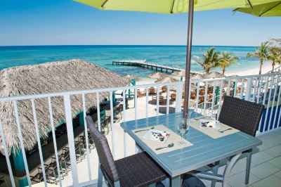 a balcony overlooking the ocean , with a dining table and chairs set up for a meal at Wyndham Reef Resort Grand Cayman