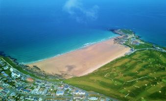 an aerial view of a sandy beach with green grass and buildings in the distance at Breakers