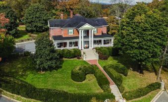 aerial view of a large red brick house surrounded by green grass and trees , located in the countryside at Hillcrest Mansion Inn