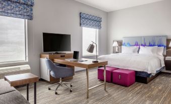 a modern hotel room with a bed , desk , chair , and tv . also a window in the room at Hampton Inn & Suites Bridgeview Chicago