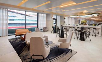 a modern lounge area with white furniture , a bar , and a view of the city at Hilton Garden Inn Silverstone