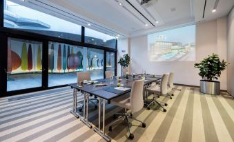 a modern conference room with a long table , chairs , and a large screen displaying an image of a building at Devero Hotel  Spa, BW Signature Collection