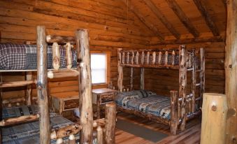 a rustic bedroom with a wooden bunk bed and a single bed on a wooden floor at Diamond Lake Cabins