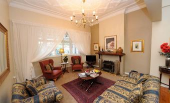 a spacious living room with multiple couches , chairs , and a fireplace , decorated in a traditional style at Oxford Lodge Vryheid