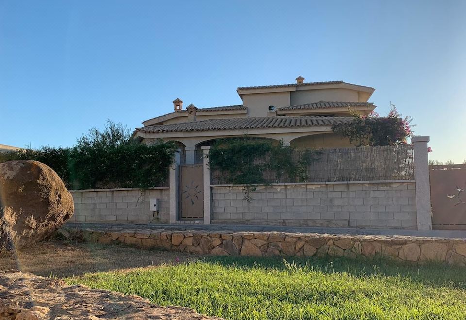 a modern , minimalist house with stone walls and a green lawn , surrounded by a stone wall and a stone path at Il Tramonto