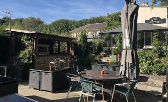 an outdoor dining area with a table , chairs , and umbrellas , surrounded by a brick building and greenery at Michelangelos