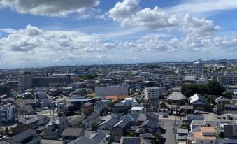 a cityscape with a mix of residential and commercial buildings under a blue sky with clouds at Toyoko Inn Meitetsu Chiryu Ekimae