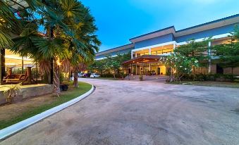 a large building with a curved roof is surrounded by trees and plants , and a parking lot in front of it at Chanalai Resort and Hotel