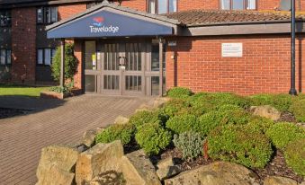 "a travelodge hotel with a blue awning , stone steps , and a sign that says "" travelodge ""." at Travelodge Sleaford