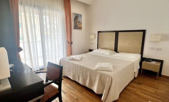 a large bed with white linens is in a room with wooden floors and a desk at Hotel Joli