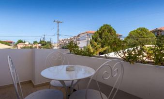 a balcony overlooking a cityscape , with a table and two chairs set up for outdoor dining at Thetis