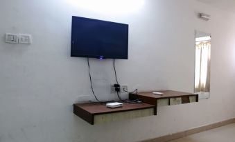 a television mounted on a wall with a wooden shelf below it and a computer monitor on the left at Hotel Princess