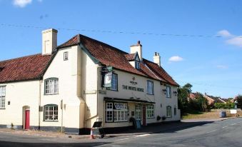 a white building with red roof and green sign , possibly a pub or a tavern at The White Horse