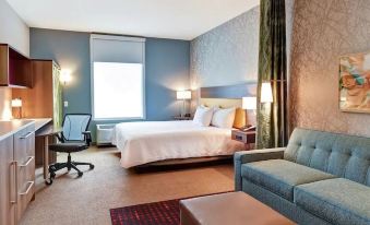 a hotel room with a large bed , a chair , and a window overlooking the city at Home2 Suites by Hilton Marysville