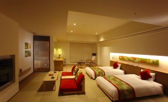 a modern hotel room with two beds , a couch , and a tv , all lit up by natural light from the windows at Hotel Mahoroba