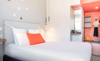 a clean and well - organized bedroom with a white bed , orange pillows , and a mirror on the wall at Kyriad Lyon Est - Saint Quentin Fallavier