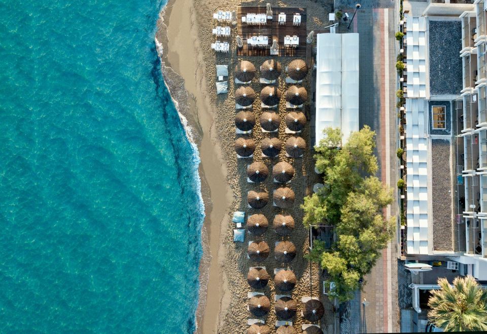 aerial view of a beach with numerous umbrellas and chairs , surrounded by the ocean and trees at Golden Star City Resort