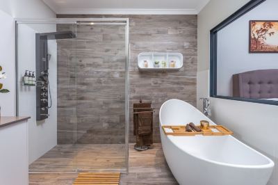 a modern bathroom with a white bathtub , wooden floor , and a glass shower enclosure at The Swan Valley Retreat