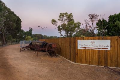 a rural setting with a wooden fence surrounding a dirt field , surrounded by trees and a barn at The Swan Valley Retreat