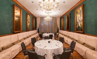 a dining room with several round tables and chairs , a chandelier hanging from the ceiling , and paintings on the walls at Shahdag Hotel & Spa