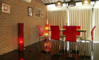 a dining room with red chairs and a wooden table , surrounded by brick walls and floor at Suan Muang Porn