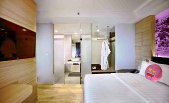 a modern bedroom with a white bed and wooden flooring , featuring a bathroom in the background at Favehotel Cimanuk Garut