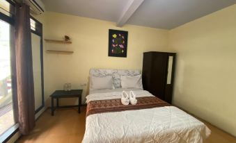 a neatly made bed with white sheets and a brown blanket is in a room with wooden floors at Adel Guest House