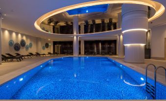 a large , blue - lit swimming pool with multiple levels and lounge chairs in a modern building at Hilton Mall of Istanbul