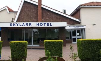the exterior of the skylark hotel with a sign and bushes in front of it at Skylark Hotel
