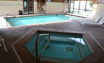 a large swimming pool with a hot tub in the middle and lounge chairs around it at Daniels Summit Lodge