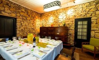 a restaurant with a stone wall and wooden table set for dining , featuring white plates and wine glasses at Inn Mahogany Creek