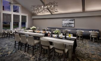 a dining room with a long dining table surrounded by chairs , and a chandelier hanging above at Residence Inn Saddle River