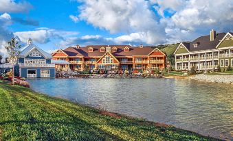 a large , multi - story building with a wooden exterior and red roof is situated near a river at Hilton Grand Vacations Club Blue Mountain Canada