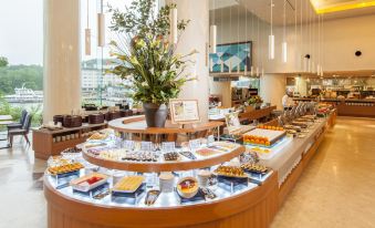 a dining area with a large buffet table filled with various food items and utensils at New Akan Hotel