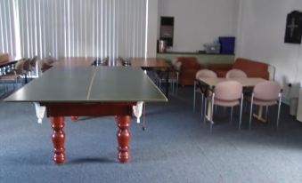 a ping pong table is set up in a room with chairs and other furniture at Lucas Heights Motel