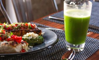 a glass of green smoothie sits on a dining table next to a plate of food at Casa San Miguel Hotel Boutique y Spa