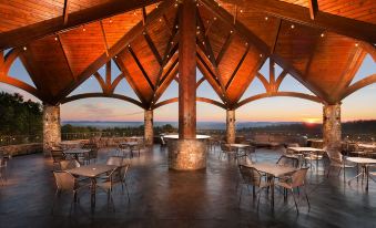 a large wooden structure with a curved roof and tables and chairs in the foreground at Aiden by Best Western @ Warm Springs Hotel and Event Center