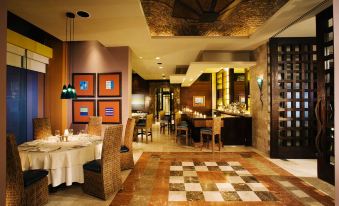 a dining room with a table set for a meal and several chairs arranged around it at Las Palomas Beach & Golf Resort