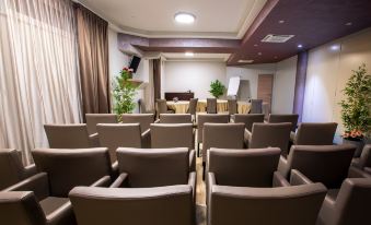 a conference room with rows of chairs arranged in a semicircle , and a podium in the center at Royal Airport Hotel
