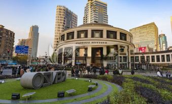 There is a large building with people walking around in front and on the sidewalk nearby at Meego Qingwen Hotel