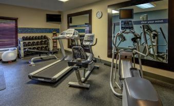 a well - equipped gym with various exercise equipment , including treadmills and weight machines , under the clock at Hampton Inn Ashland