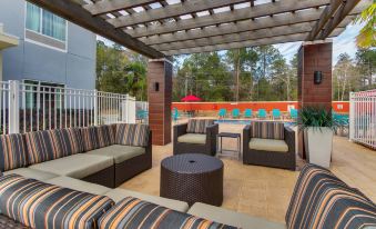 a patio area with several couches and chairs arranged around a pool , creating a comfortable outdoor space at TownePlace Suites Mobile Saraland
