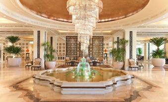 a luxurious hotel lobby with a large chandelier , multiple potted plants , and a fountain in the center at Dusit Thani Hua Hin