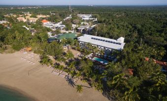 a bird 's eye view of a resort with a pool , buildings , and palm trees on a beach at Emotions by Hodelpa - Juan Dolio