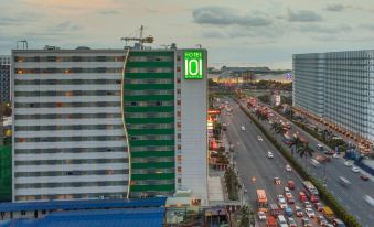 a large green building with the number 1 0 on it is surrounded by cars and traffic at Hotel 101 Manila