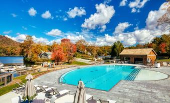 an outdoor swimming pool surrounded by a wooden deck , with several lounge chairs and umbrellas placed around it at The Greystone Inn