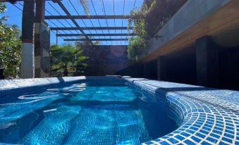 a swimming pool with a blue mosaic tile pattern is surrounded by a wooden deck and greenery at Las Jaras Aguas Termales