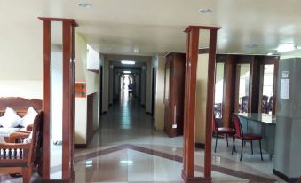 a hallway with wooden pillars on the left and another floor leading to another room at Rawanda Resort