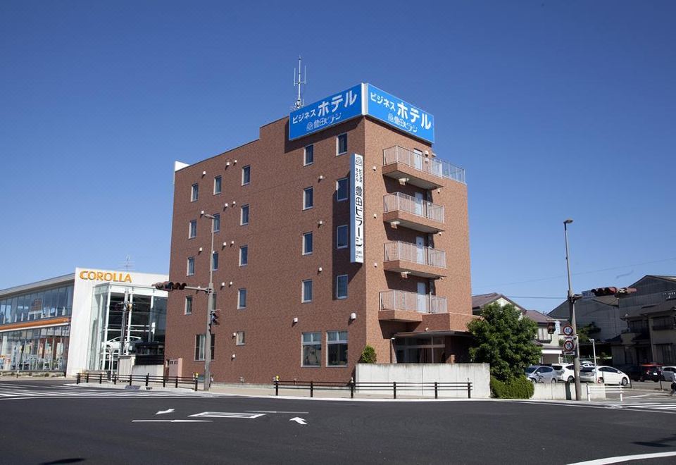 a brick building with a blue sign on the side , located in a city setting at Toyota Village